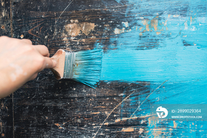 Close up paintbrush in hand and painting on the wooden table.