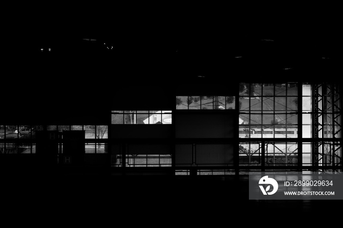 Greyscale shot of a dark room with glass windows