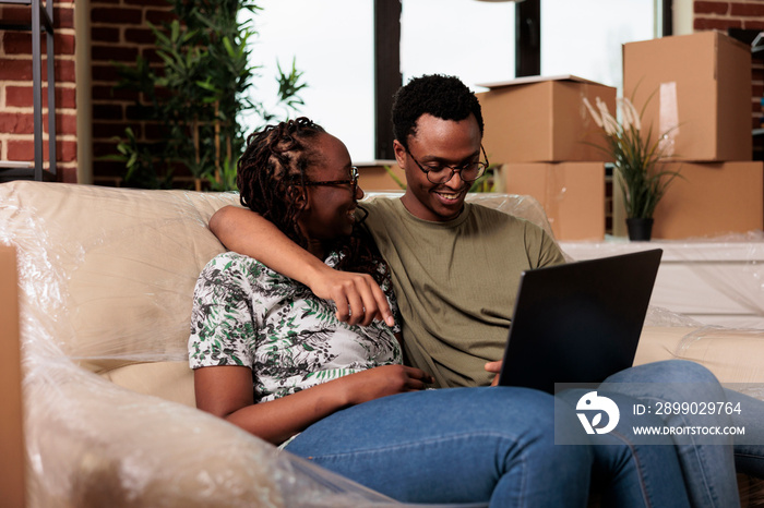 Happy married couple finding furniture on online website, shopping on laptop to decorate rented flat