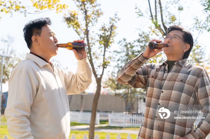 两个老年男人站在露营地喝啤酒