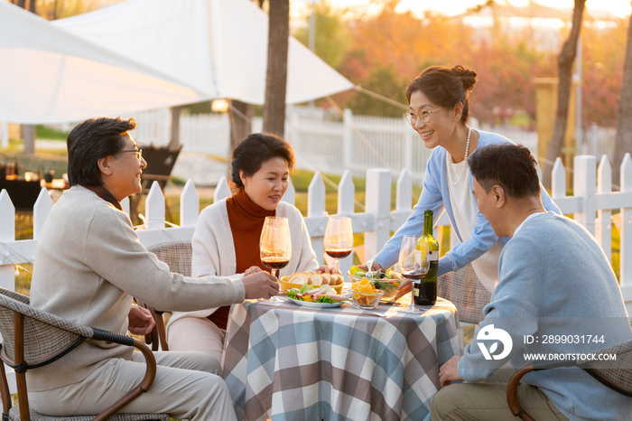 夕阳下中老年朋友在庭院里聚会喝酒聊天