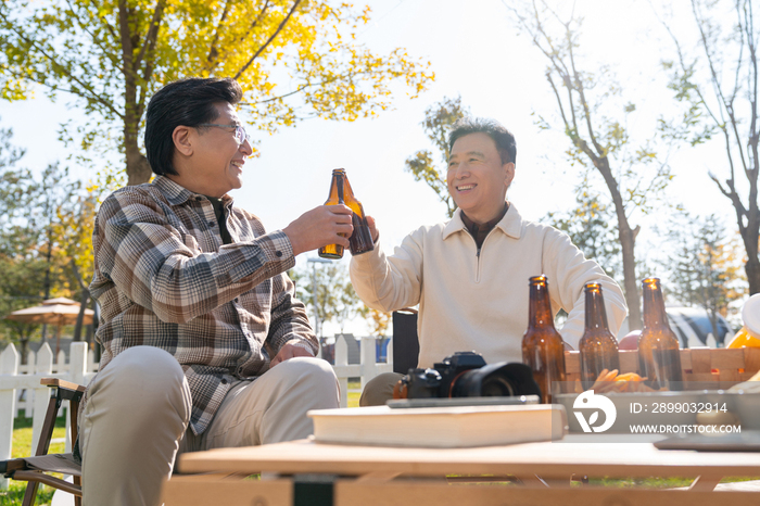 两个老年男人坐在露营地喝啤酒