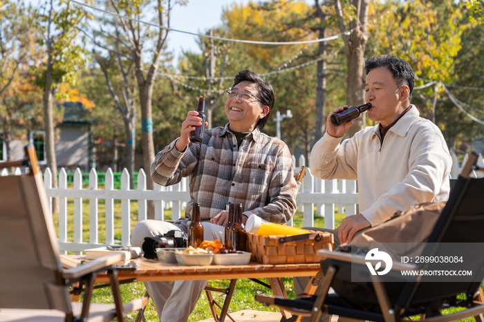 两个老年男人坐在露营地喝啤酒