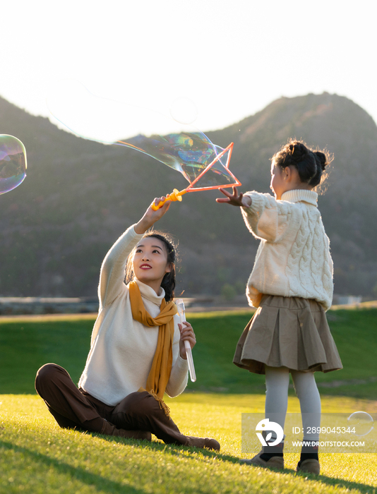 母亲和孩子在草地上玩泡泡