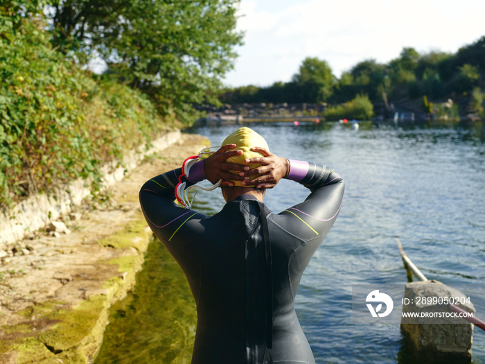 Woman in wetsuit putting on swimming cap