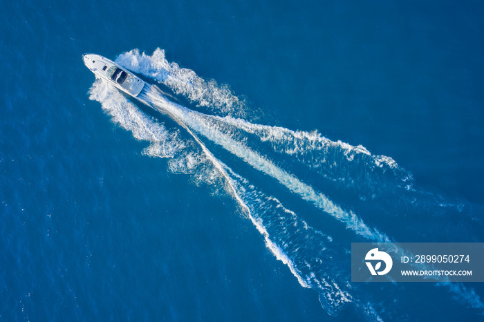 Aerial view luxury motor boat. Drone view of a boat sailing. Top view of a white boat sailing to the blue sea. Motor boat in the sea. Travel - image.