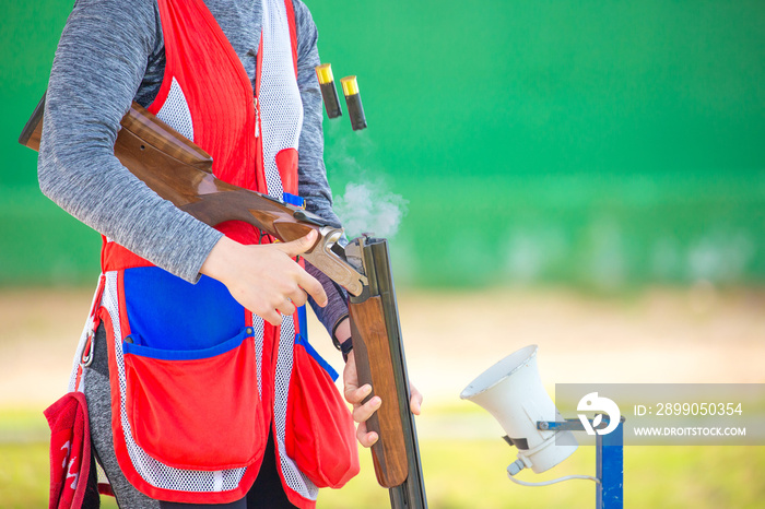 Clay pigeon shooting. An athlete shoots a gun at moving targets isolated on a green background, sport gun shooting, with a place for text, clay pigeon shooting.