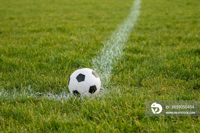 Classic foot ball on a green grass pitch. Outdoor training concept. Nobody. Sport theme background