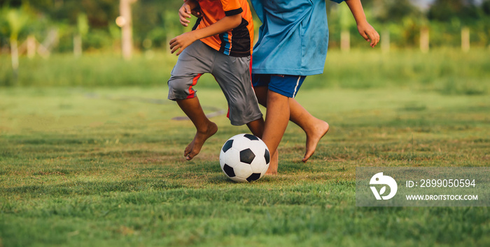 An action sport picture of a group of kids playing soccer football for exercise in community rural area under the sunset.