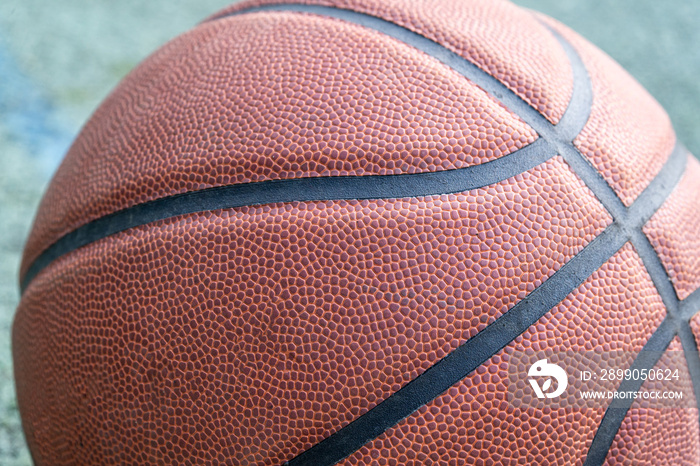 Orange basketball ball on the ground. Close-up ball on the red court. Basketball on the street or indoor court. Sports gear without people. Minimalism. Template, sport background