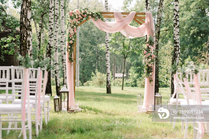 A lot of white chairs and the arch for a wedding