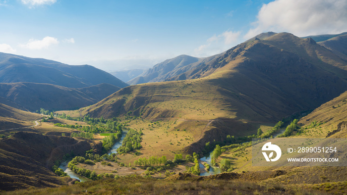 Sunny summer landscape. Beautiful hills, fields and river. Coruh River in Anatolia region, Turkey.Sunrise. Quiet morning.Calm. Warm sunlight.Clear blue sky with clouds.