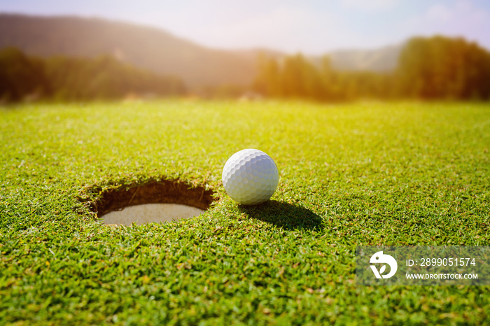 Golf ball on lip of hole over beautiful green loan