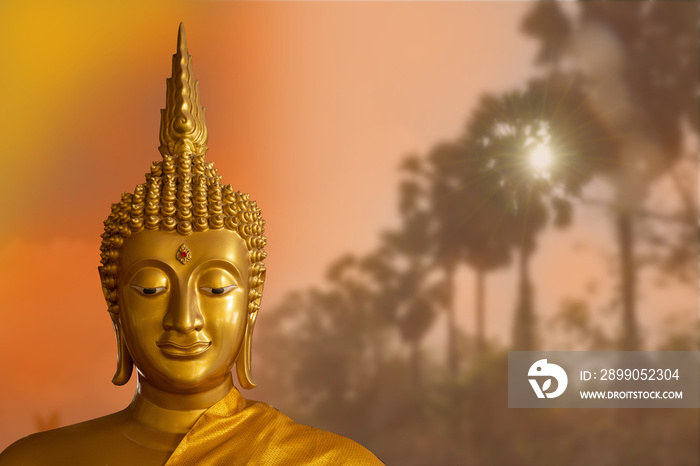 Buddha statue standing on a pink lotus flower in the river and the golden sky background.