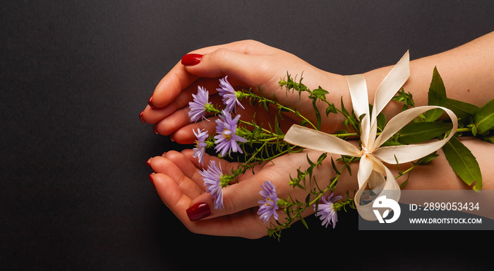 Beautiful female hands tied on a black background. Top view with place for text.