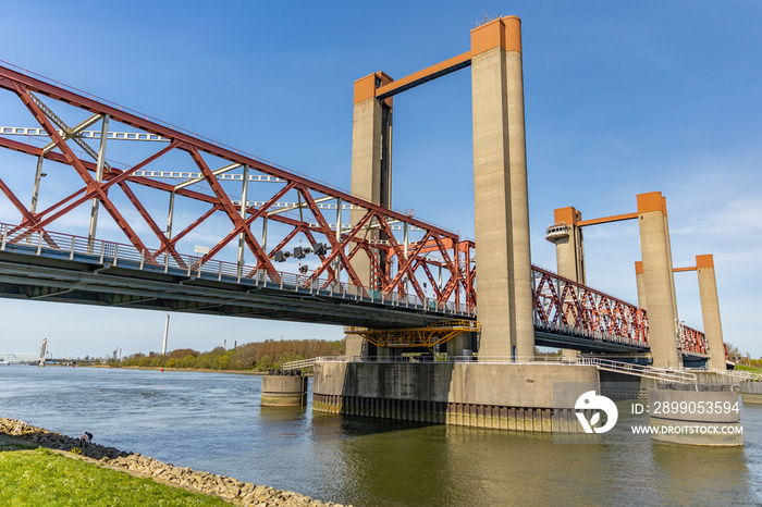 A beautiful red old bridge, river Old Maas and ship with containers in Spijkenisse in Holland