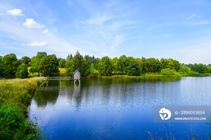 Kranicher Teich in the spa gardens of Hahnenklee. Idyllic landscape by the lake with an old Striegelhaus. Nature by the water with a Striegelanlage.