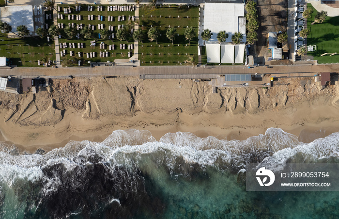 Aerial view of ocean waves breaking on a sandy beach. Beach erosion after coastal flooding.