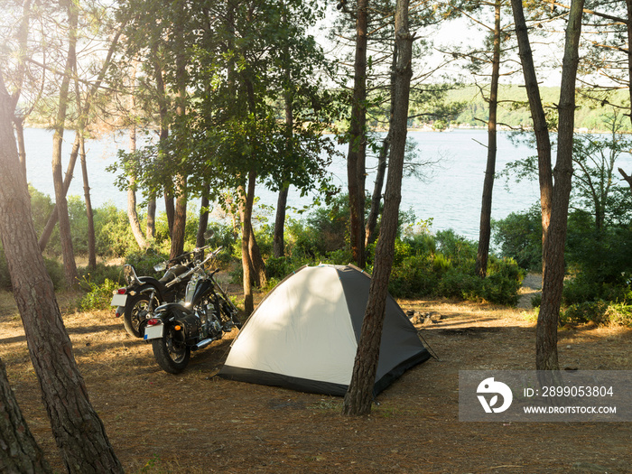 Camping in the forest by the sea. Motorcycle tent camping activity. Tent and off road adventure motorcycle in the forest. Active lifestyle outdoor concept