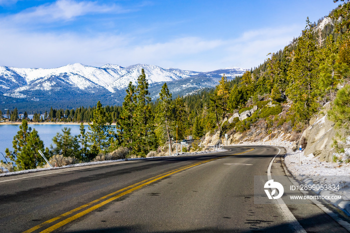 Travelling on the shoreline of Lake Tahoe on a winter day; Sierra mountains covered with snow visible in the background