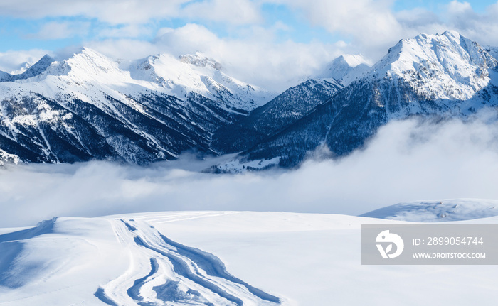 Mountain ski resort. Snowcat trail on snow slope. Snowy mountains. Ski resort landscape on clear sunny day. Panoramic view of mountains near Brianson, Serre Chevalier resort. Winter vacation..