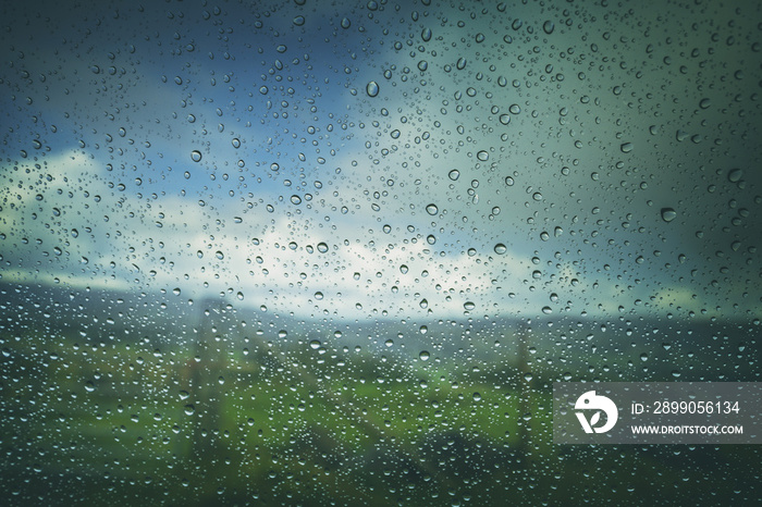 Raindrops on Car Window with Blurry Landscape in Background