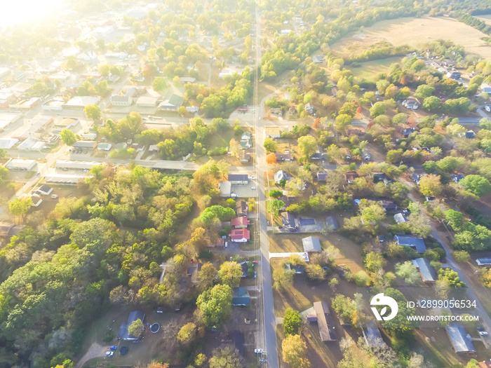 Scenic aerial green suburban area of Ozark, Arkansas, USA. Top overhead residential neighborhood tightly packed homes, driveway surrounded by lush tree flyover in autumn sunset. View from East side