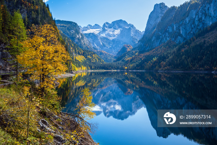 Peaceful autumn Alps mountain lake with clear transparent water and reflections. Gosauseen or Vorderer Gosausee lake, Upper Austria. Dachstein summit and glacier in far.