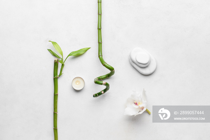 Spa stones with bamboo branches, candle and flower on white background