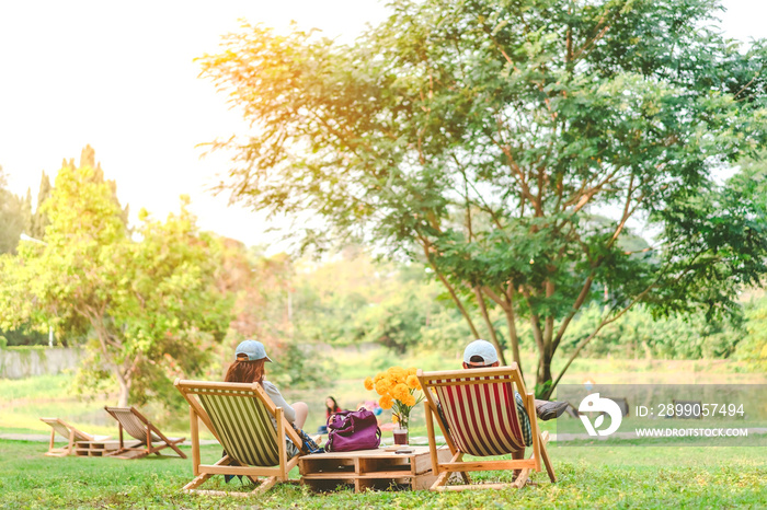 Happiness couple on a summer holiday sitting on  garden chairs to relax in the public park.