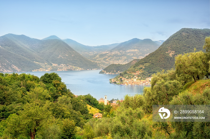 Picturesque summer landscape in Italy. Lago d’Iseo. Aerial view of Lake Iseo and forested mountains, various villages scattered along the mountain slopes and along the coast.