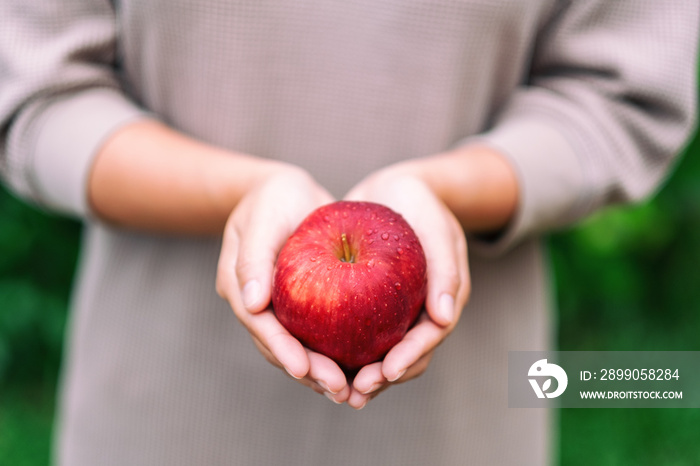 A woman holding a fresh red apple in hands