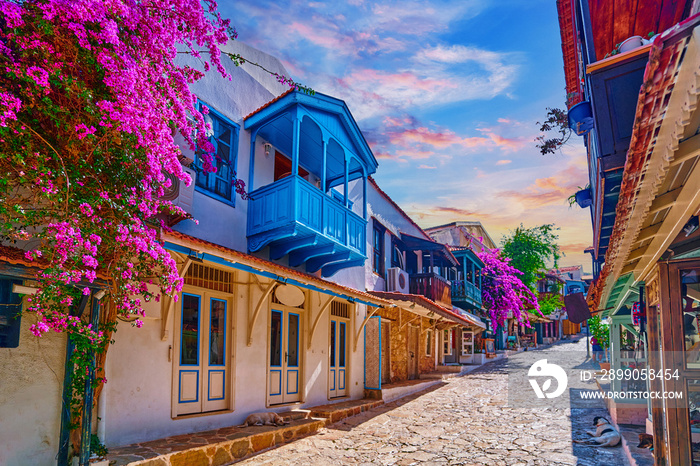 Old colored street view. White houses with wooden blue balconies and pink flowers in Kas city, Turkey
