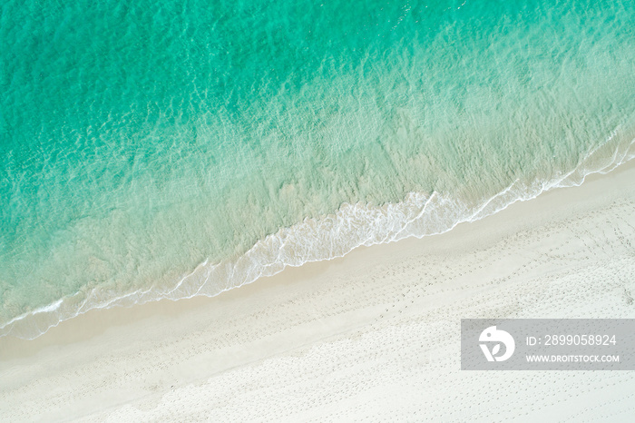 Aerial drone view of sandy white beach in summer with brilliant blue turquoise waters