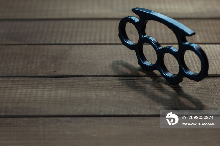 Brass knuckles on a beautiful brown wooden background.