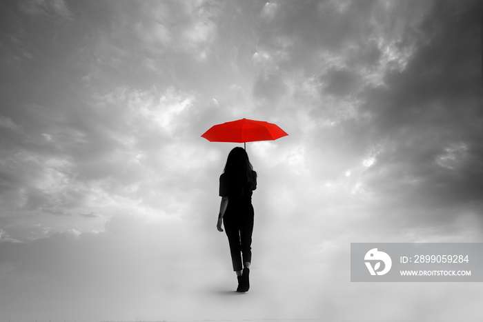 Silhouette of girl with umbrella in a dreamlike context - red umbrella with leaden sky - color contrast.