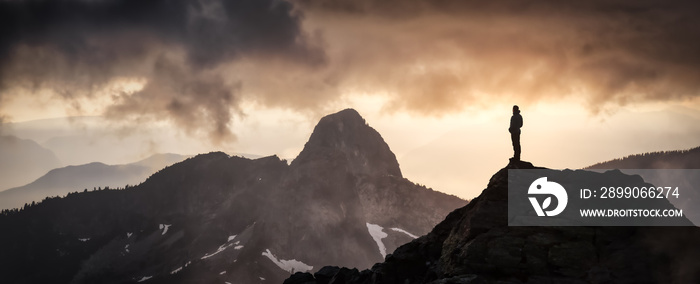 Magical Fantasy Adventure Composite of Man Hiking on top of a rocky mountain peak. Background Landscape from British Columbia, Canada. Sunset Dark Dramatic Colorful Sky