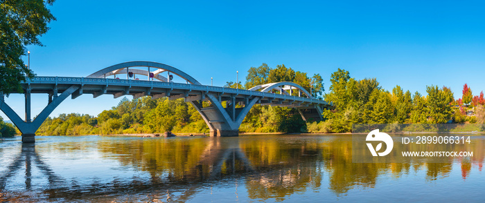 Rogue River Bridge, spanning Redwood Highway 25 in Grants Pass, Josephine County, Oregon. The arching bridge and autumn forest foliage reflected on Rogue River.