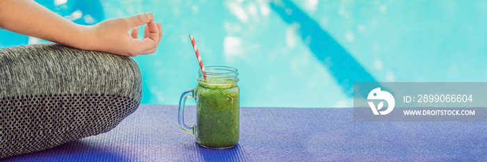 Closeup of a woman’s hands during meditation with a green smoothies of spinach, orange and banana on the background of the pool BANNER, long format