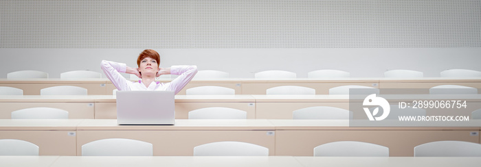 student in high school auditorium at school with white laptop