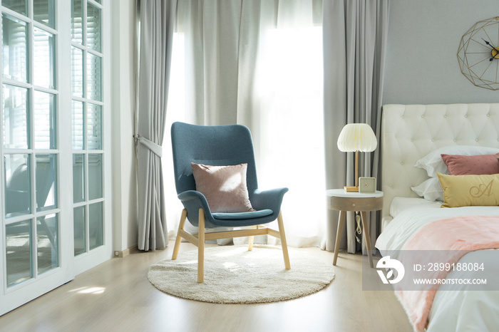 Blue Scandinavian armchair sitting in bedroom with side table and carpet