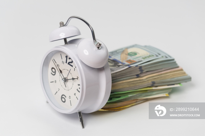 Time is money concept, us dollars, euro banknotes and alarm clock