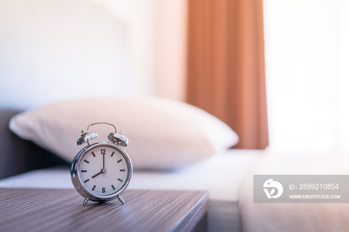 Metal Alarm clock on white bed 8 am.