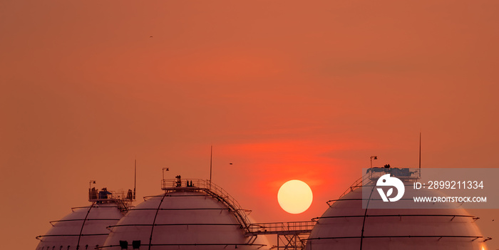 Industrial gas storage tank on orange sunset sky. LNG or liquefied natural gas storage tank. Spherical gas tank in petroleum refinery. Above-ground storage tank. Natural gas storage industry.