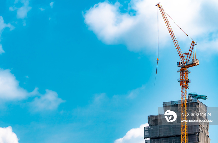 Construction site with crane and building. Real estate industry. Crane use reel lift up equipment in construction site. Building made of steel and concrete. Crane work against blue sky and white cloud