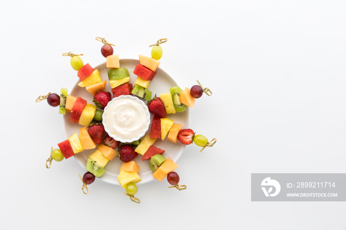 Bright colourful fresh fruit kebabs isolated against a white background.