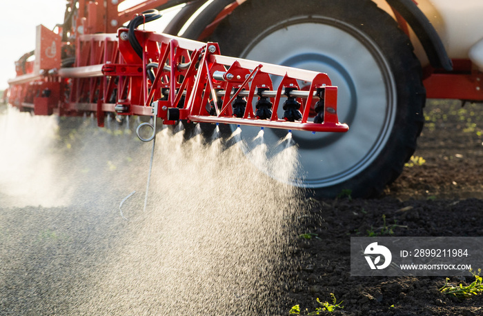 Tractor spraying land in sunset.