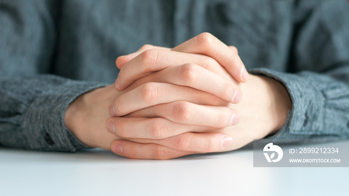 the young man’s hands are folded on the table