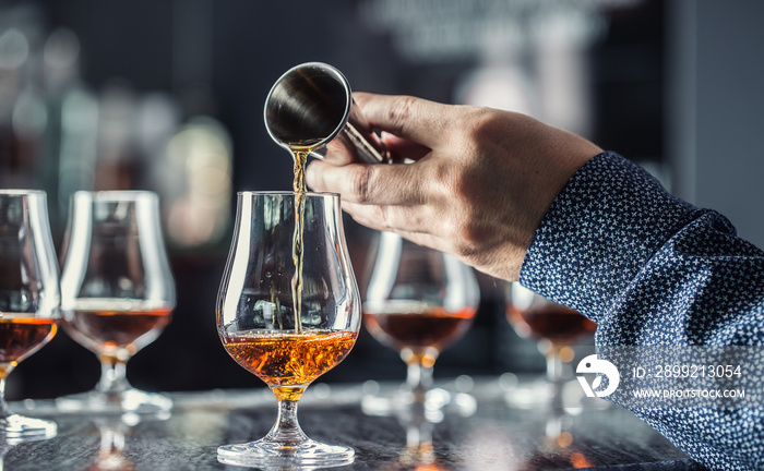 Bartender hand pouring alcoholic drink in nightclub, bar or pub.