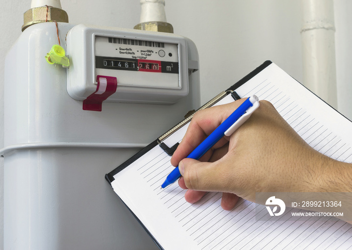 Person reading the gas meter in the private house, counter for distribution domestic gas. Cropped image, selective focus.